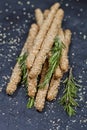 Italian grissini or salted bread sticks with sesame and rosemary herb on black board background
