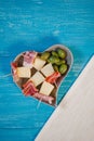 Italian ham, melon and green olives in a heart shaped plate on a wooden background Royalty Free Stock Photo