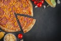 Italian homamade pizza with one piece and ingredients. Italian pizza on a dark gray black background