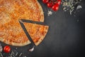 Italian homamade pizza with one piece and ingredients. Italian pizza on a dark gray black background