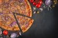 Italian homamade pizza with one piece and ingredients. Italian pizza on a dark gray black background