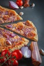 Italian homamade pizza with one piece and ingredients. Italian pizza on a dark gray black background