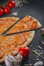 Italian homamade pizza with one piece and ingredients. Italian pizza on a dark gray black background