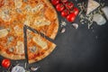 Italian homamade pizza with one piece and ingredients. Italian pizza on a dark gray black background