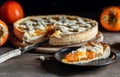 Italian homemade persimmon tart or crostata with one piece on the black plate, fruits over wooden background Royalty Free Stock Photo