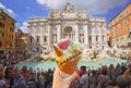 Italian ice - cream cone held in hand on the background of famous Trevi Fountain