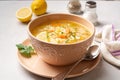 Italian lemon chicken orzo soup in bowl on concrete background