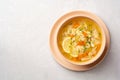 Italian lemon chicken orzo soup in bowl on concrete background