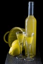 Italian limoncello in a shot glass on a black wooden background