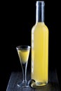 Italian limoncello in a shot glass on a black wooden background