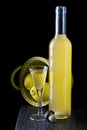 Italian limoncello in a shot glass on a black wooden background