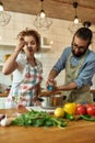 Italian man adding pepper, spice to the soup while woman tasting it. Couple preparing a meal together in the kitchen Royalty Free Stock Photo