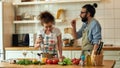 Italian man, chef cook drinking white wine while woman using hand blender. Young couple preparing a meal together in the Royalty Free Stock Photo