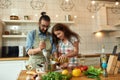 Italian man, chef cook using hand blender while preparing a meal. Young woman, girlfriend in apron pouring olive oil in Royalty Free Stock Photo