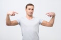 Italian man in white t-shirt, standing, pointing himself and looking with serious egoist face. Royalty Free Stock Photo