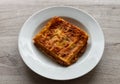 Italian meat Lasagne in a white dish on wooden background. Portion of traditional Lasagna