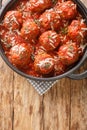 Italian meatballs with parmesan in spicy tomato sauce close-up in a frying pan. Vertical top view Royalty Free Stock Photo
