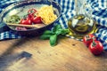 Italian and Mediterranean food ingredients on wooden background.Cherry tomatoes pasta, basil leaves and carafe with olive oil. Royalty Free Stock Photo