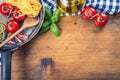 Italian and Mediterranean food ingredients on wooden background.Cherry tomatoes pasta, basil leaves and carafe with olive oil. Royalty Free Stock Photo