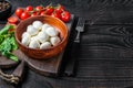 Italian mini Mozzarella cheese balls, basil and tomato cherry ready for cooking Caprese salad. Black wooden background Royalty Free Stock Photo