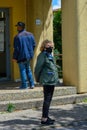 Old woman with black face mask waits outside the post office. An italian lady waits in line, social distancing for public service