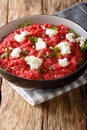 Italian Orzotto with beets, goat cheese and herbs close-up on a plate. vertical