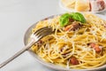 Italian pasta carbonara made of spaghetti, bacon, parmesan cheese and basil in a plate with fork on white marble table Royalty Free Stock Photo