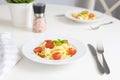 Italian pasta, pasta with cherry tomatoes and a sprig of basil in a white plate on a white table. Vegetarian food. Lunch Royalty Free Stock Photo