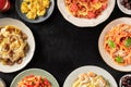 Italian pasta dishes forming a frame for copy space, overhead shot on a dark background. Pastas with meat, vegetables, seafood,