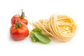 Italian pasta nest, tomato and basil leaves. Uncooked spaghetti nest