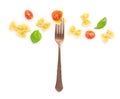 Italian pasta. An overhead photo of a vintage style fork with farfalle, basil, and cherry tomatoes on a white background