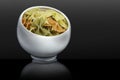 Italian pasta in a porcelain cup. Macaroni in the form of multi-colored bows. Black background. Royalty Free Stock Photo