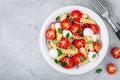 Italian pasta salad with tomatoes, mozzarella cheese, red onion and basil. Top view Royalty Free Stock Photo