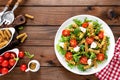 Italian pasta salad with wholegrain fusilli, fresh tomato, cheese, lettuce and broccoli on wooden rustic background Royalty Free Stock Photo