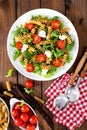 Italian pasta salad with wholegrain fusilli, fresh tomato, cheese, lettuce and broccoli on wooden rustic background Royalty Free Stock Photo