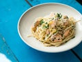 Italian pasta with salmon, parsley, lemon rind and cheese. Fresh pasta with salmon in a creamy sauce in a saucer on a blue wooden