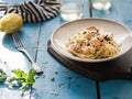 Italian pasta with salmon, parsley, lemon rind and cheese. Fresh pasta with salmon in a creamy sauce in a saucer on a blue wooden