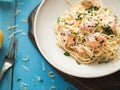 Italian pasta with salmon, parsley, lemon rind and cheese. Fresh pasta with salmon in a creamy sauce in a saucer on a blue wooden