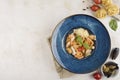 Italian pasta with seafood and fresh basil on a blue plate with a napkin on a light background Royalty Free Stock Photo