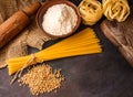 Italian pasta, spaghetti, fettuccine, wheat, rolling pin, flour on a textured background. Still life in a rustic style. Top view.