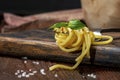 Italian pasta spaghetti on fork with basil on wooden board