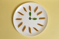 Italian pasta time. Italian penne integral and basil leaves on a white plate on a yellow background.