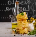 Italian pasta in a vertical serving, garlic, olive oil, green olives, rosemary sprig and black peppercorns on a white background. Royalty Free Stock Photo