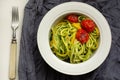 Italian Pasta with zucchini noodles with Avocado Sauce pesto and roasted tomato in white plate. Top view gray textile Royalty Free Stock Photo