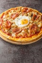 Italian Pizza Bismarck topped with tomato sauce, melted cheese, egg, mushrooms, ham close-up on a wooden board. Vertical Royalty Free Stock Photo