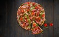 Italian pizza with ham, tomatoes, cheese and herbs on vintage wooden background. Top view Royalty Free Stock Photo