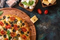 Italian pizza with ingredients. Mazzarella cheese, tomatoes. On a wooden board, on a dark green background. Top view with