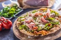 Italian pizza with prosciutto arugula tomatoes and parmesan on w