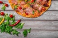 Italian pizza on a rustic table background, close-up. A half of meat pizza with salad leaves and hot chili pepper. Copy Royalty Free Stock Photo