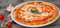 Italian pizza with tomato topped with melted golden cheese, herbs and basil